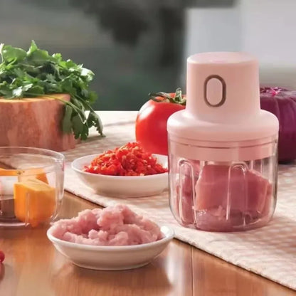 Pink manual food chopper on a kitchen counter with chopped ingredients and vegetables.