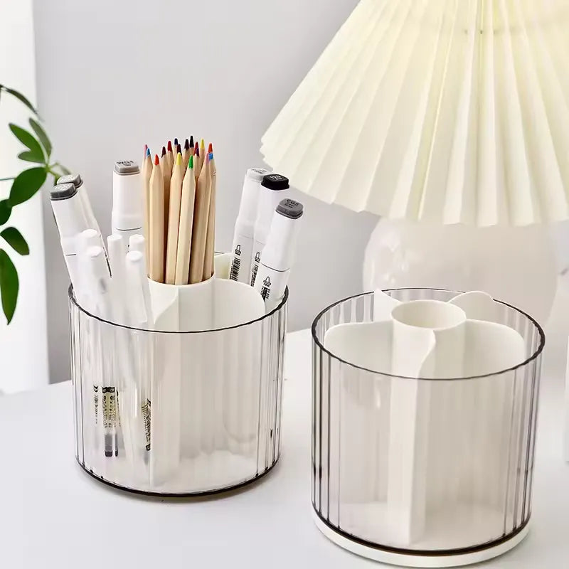Two white three-compartment desk organizers with clear ribbed plastic sides, shown on a white tabletop with stationery and a pleated lamp in the background.
